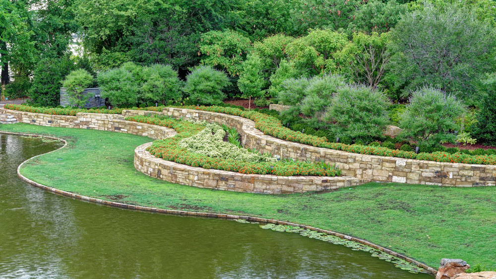 a pond surrounded by a stone garden wall | Southern Botanical