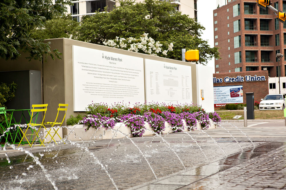 a city street with a fountain and flowers | Southern Botanical
