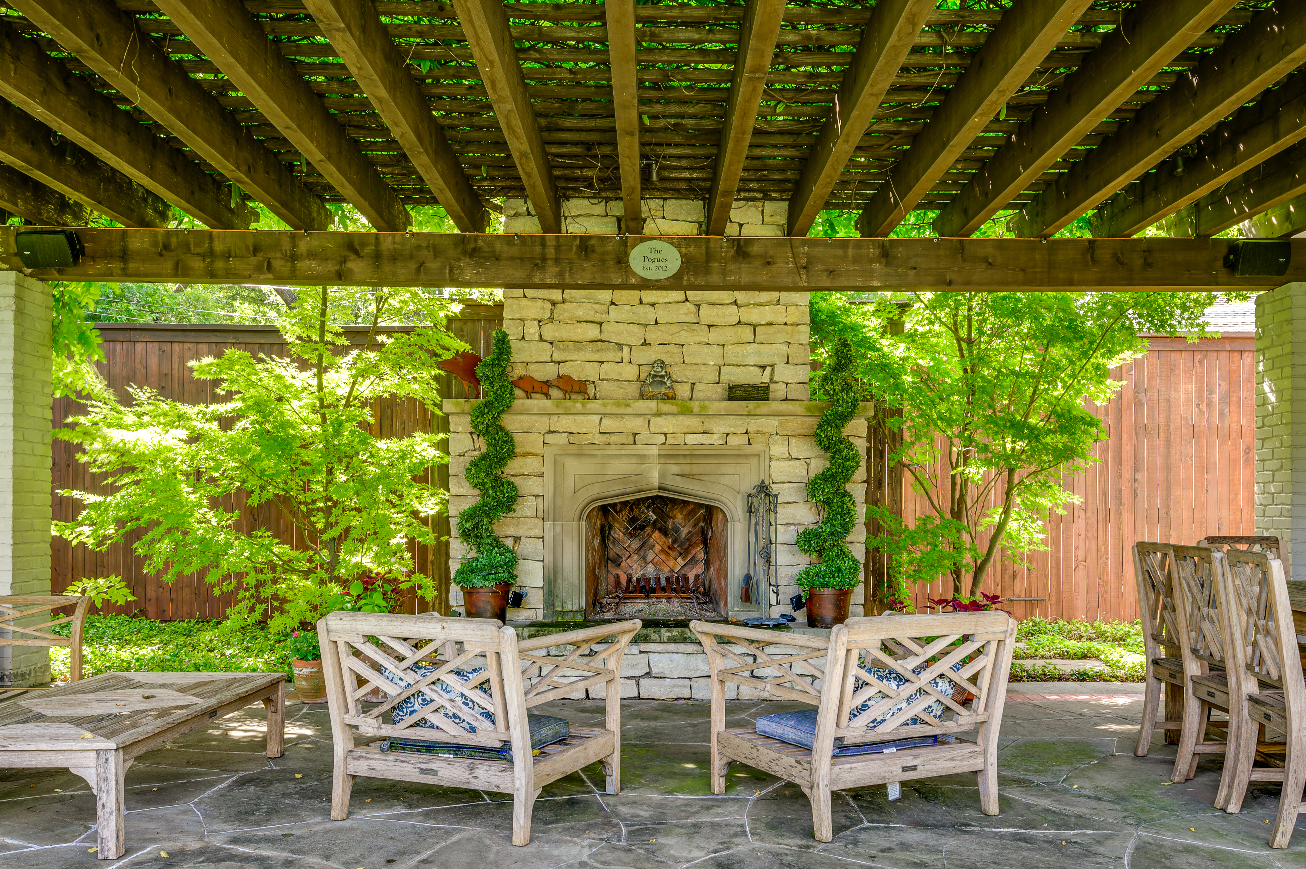 a patio with a fire place and chairs | Southern Botanical