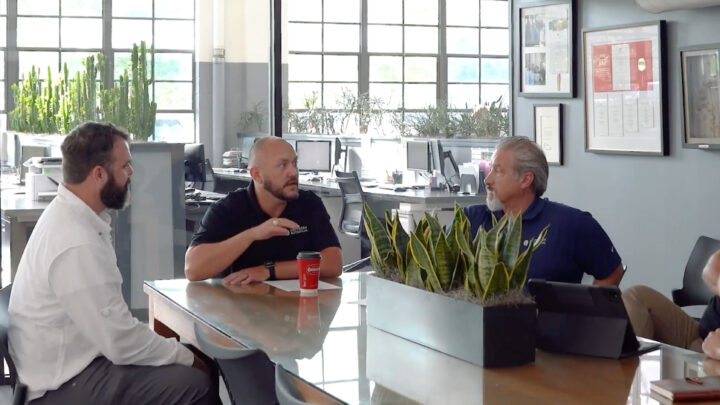 a group of men sitting around a table talking | Southern Botanical